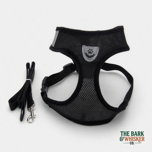 Black dog harness with leash on a white background, branded 'The Bark & Whisker Co'.